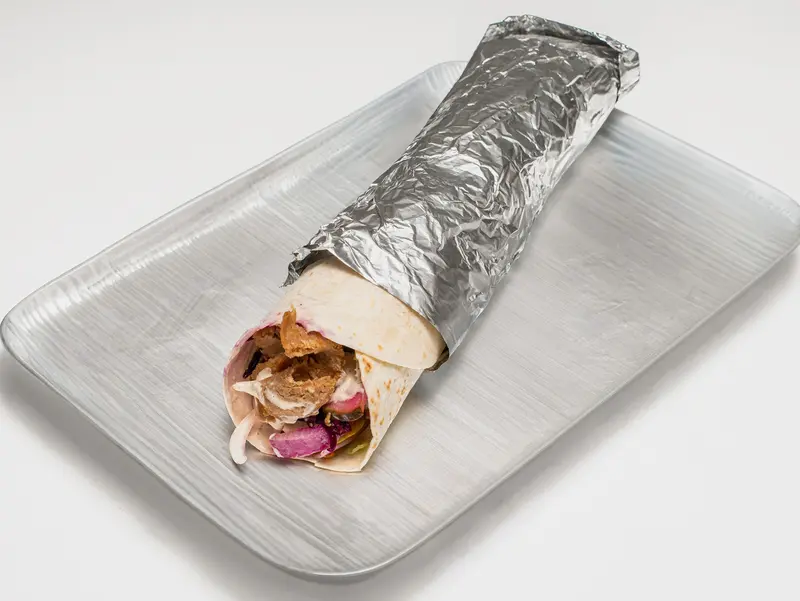 Kebabrulle inslagen i folie på en bricka, med fyllningen synlig i ena änden